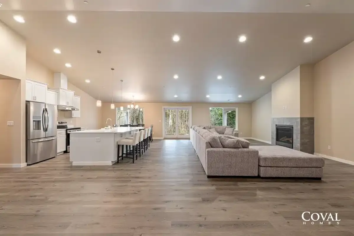 Spacious modern open-concept kitchen and living room with white island, gray sectional, and hardwood floors