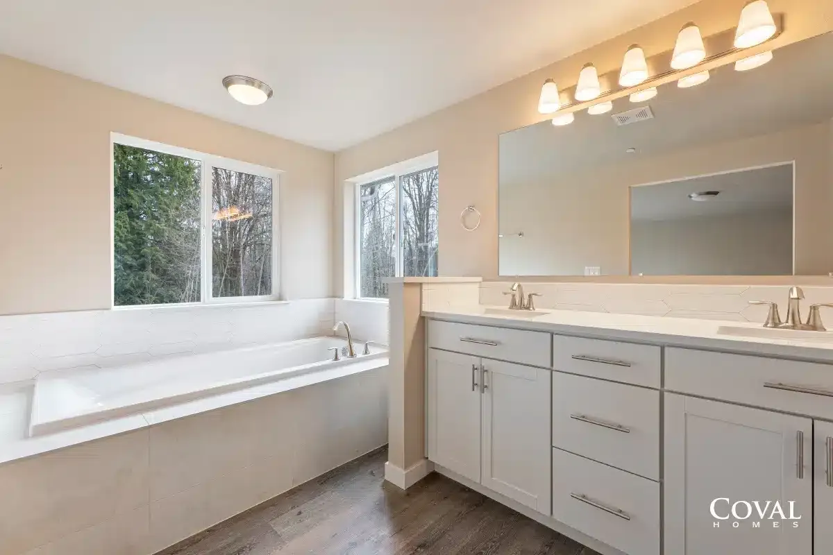 Bright modern bathroom with a soaking tub, white vanity, and large mirror under vanity lights