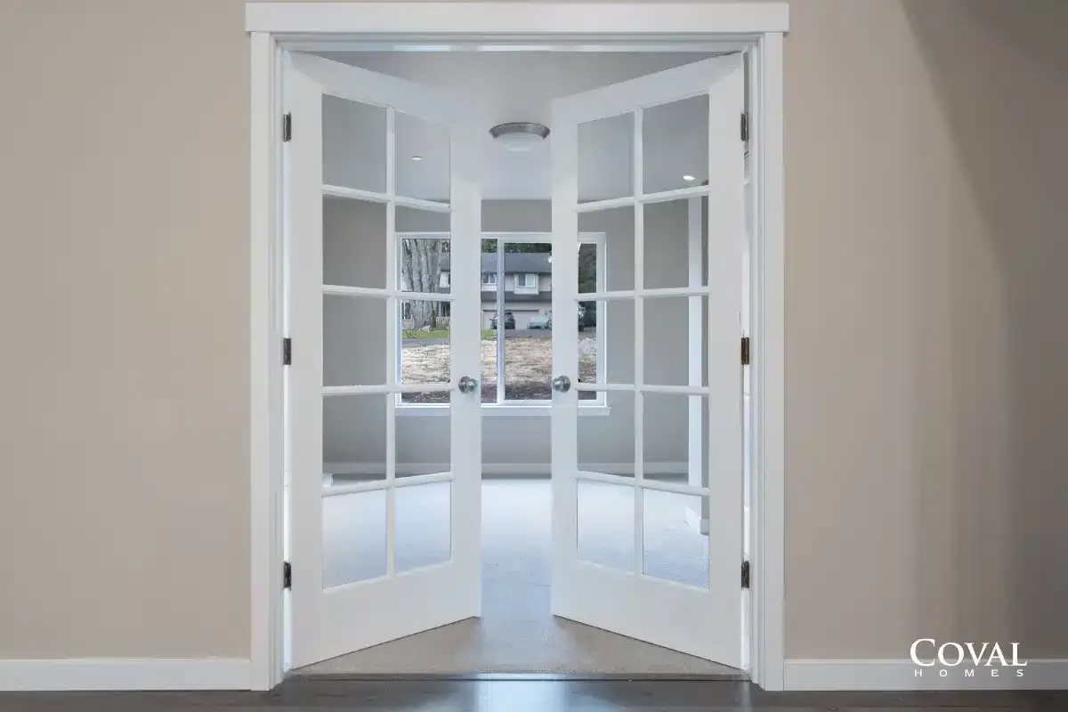 White French doors open into a bright empty room with a window view.
