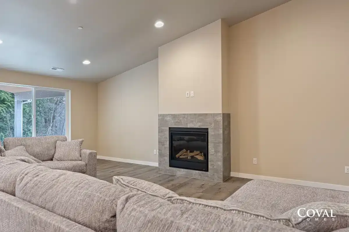 Spacious beige living room with stone fireplace, carpeted floor, and large windows.