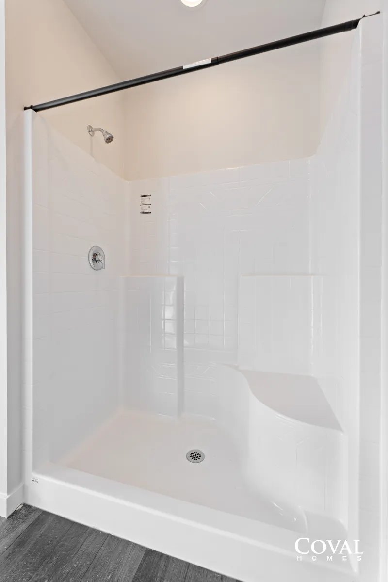 White-tiled shower stall with a black curtain rod and built-in corner shelf.