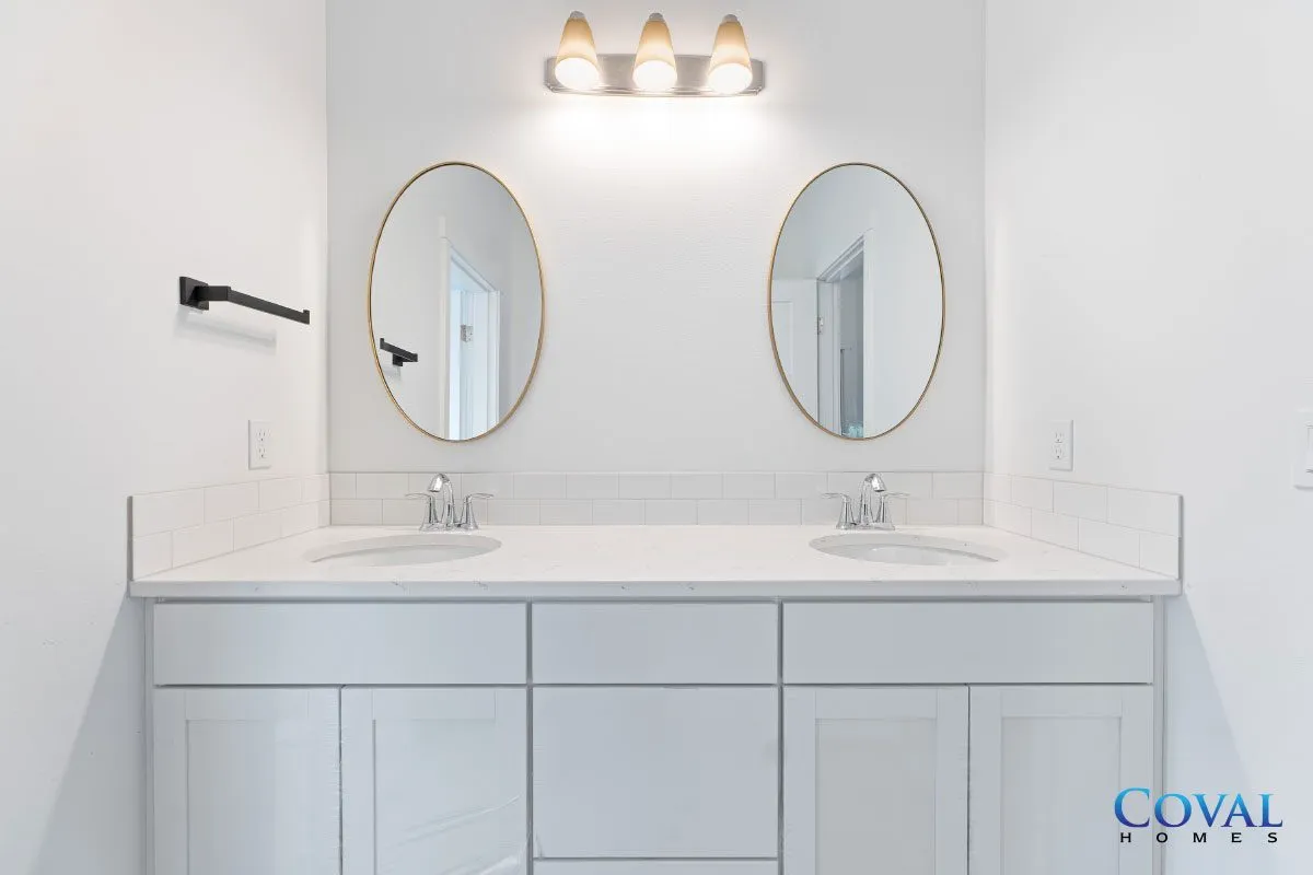 Modern white bathroom vanity with double oval mirrors and wall-mounted lights