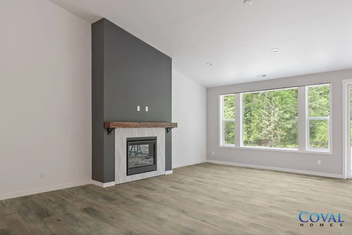 Modern living room with gray fireplace and large windows overlooking greenery