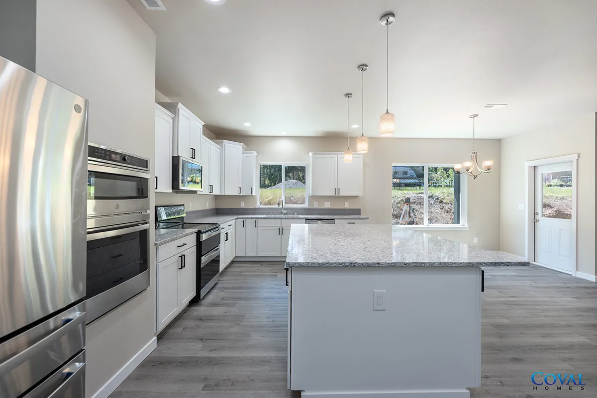Bright modern kitchen with stainless steel appliances, white cabinets, and a large island under pendant lights