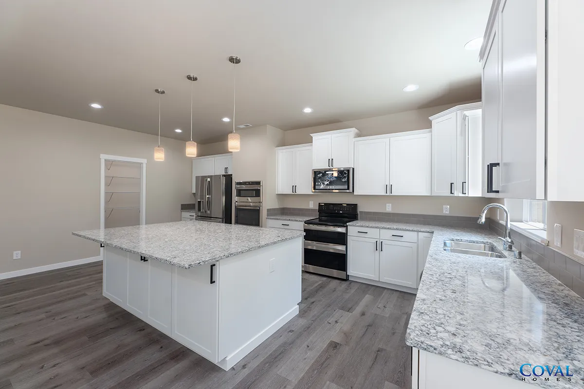 Modern white kitchen with gray island, granite countertops, stainless appliances, and pendant lights