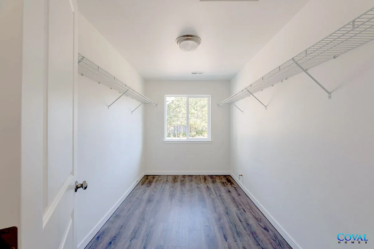 Empty white walk-in closet with wire shelves, window, and wood-look floor