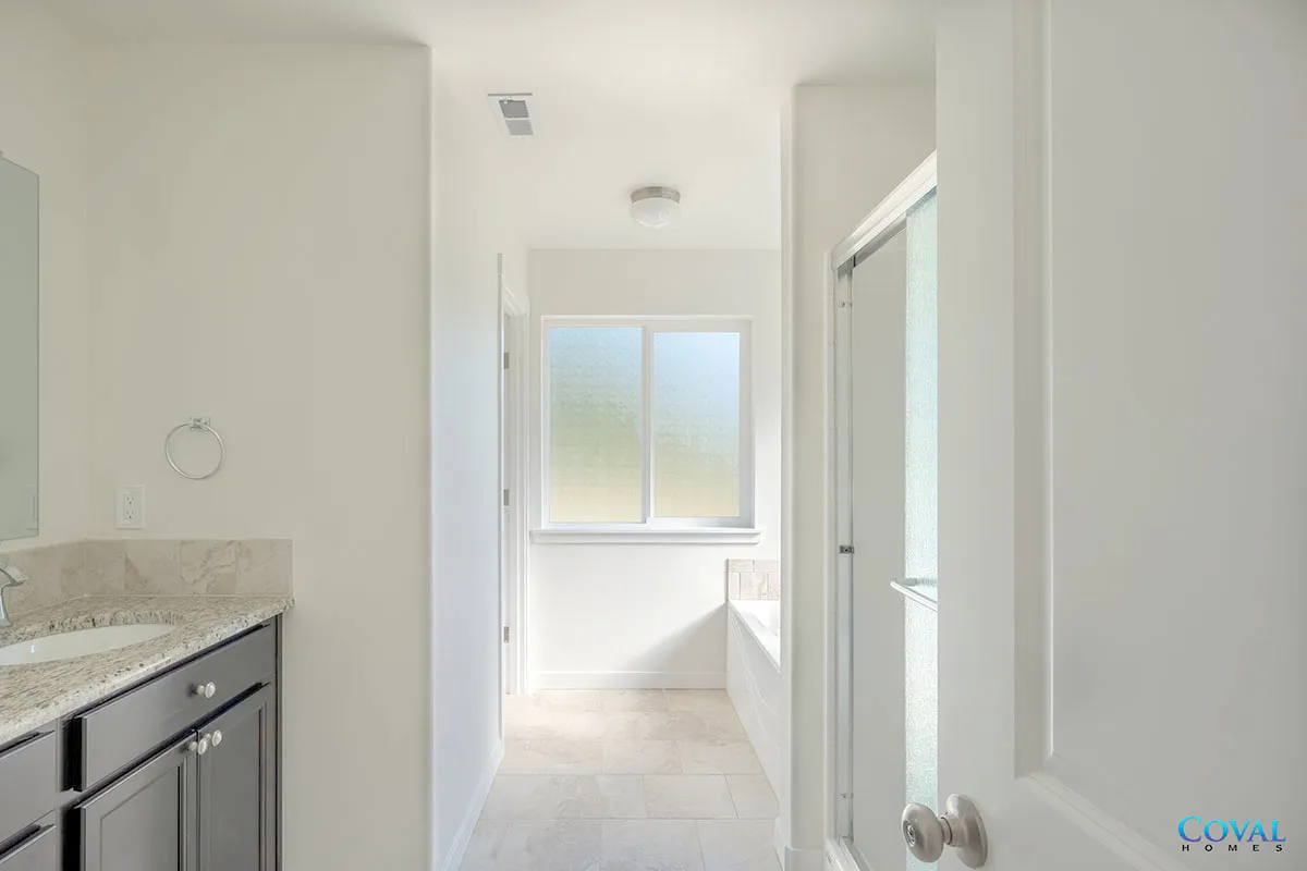 Bright white bathroom hallway with vanity, mirror, and window at the end