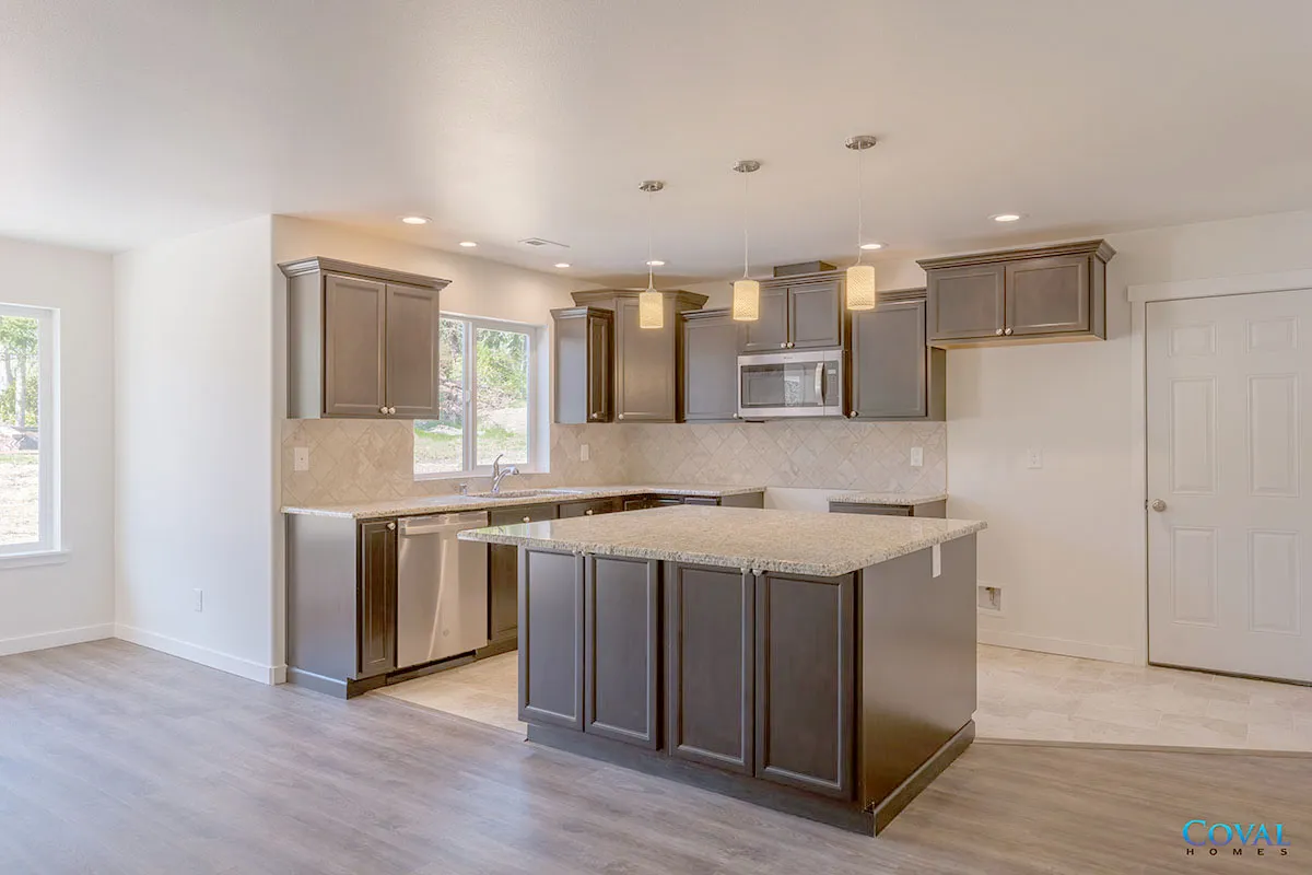 Modern kitchen with gray cabinets, island, granite countertops, and stainless steel appliances.