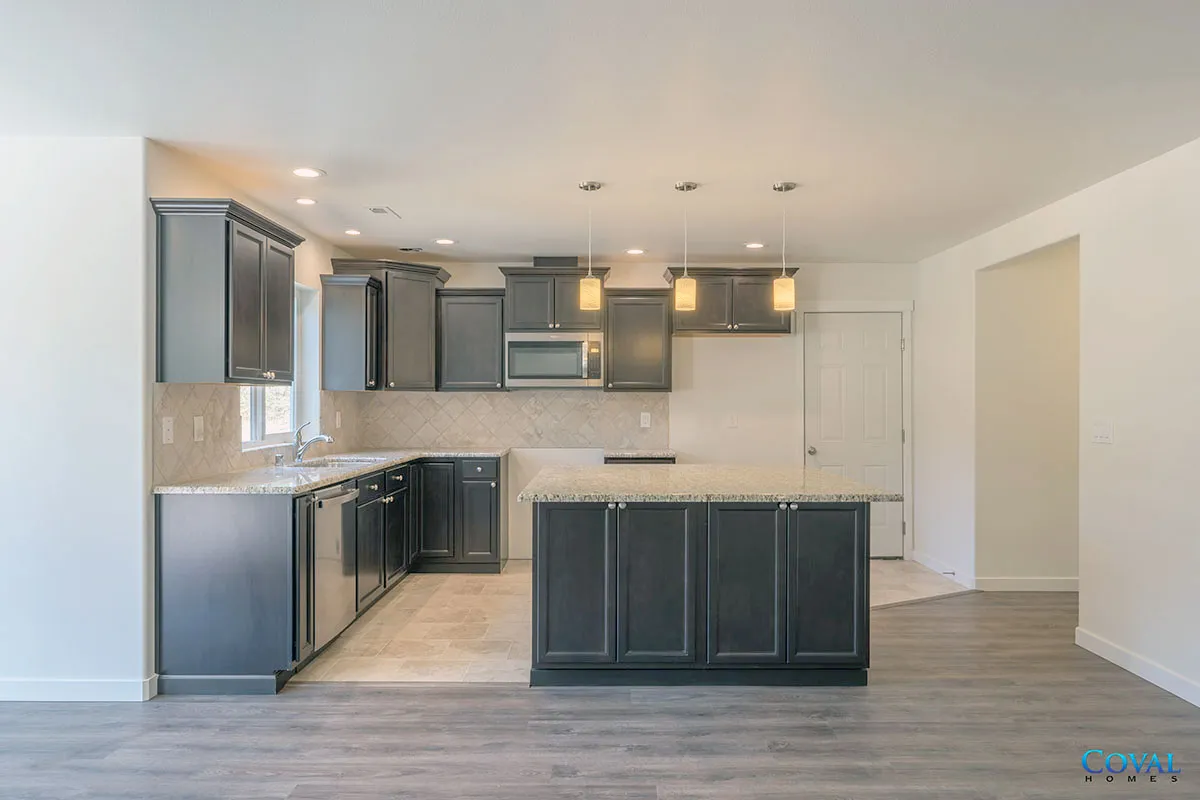Modern kitchen with dark cabinets, light countertops, and an island in an open living space