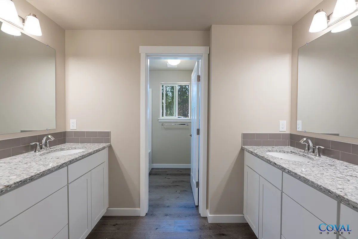 Modern double vanity bathroom with white cabinets, granite counters, and a doorway to a tub area