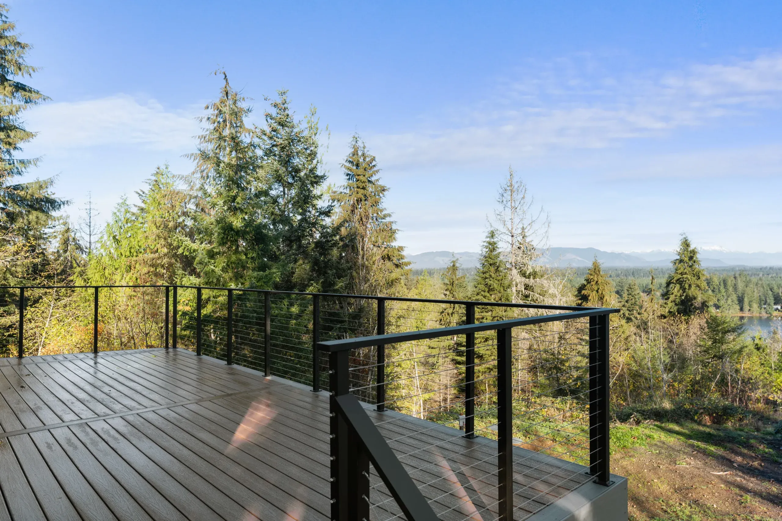 Wooden deck overlooking a forested valley under a blue sky