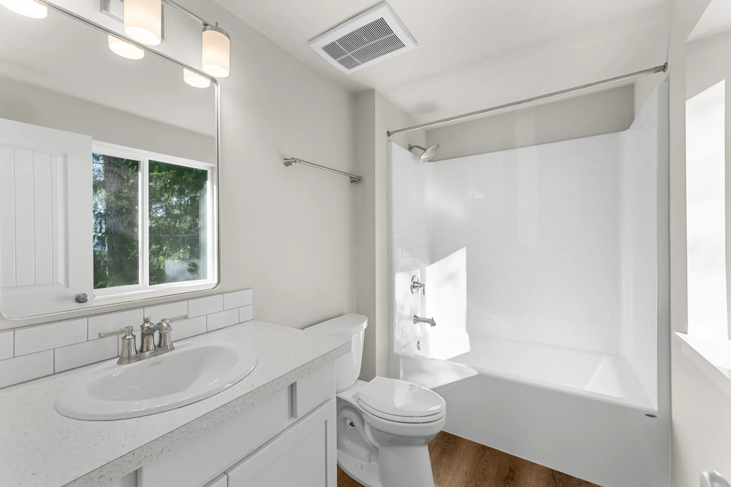 Bright white bathroom with vanity, mirror, window, and shower curtain.