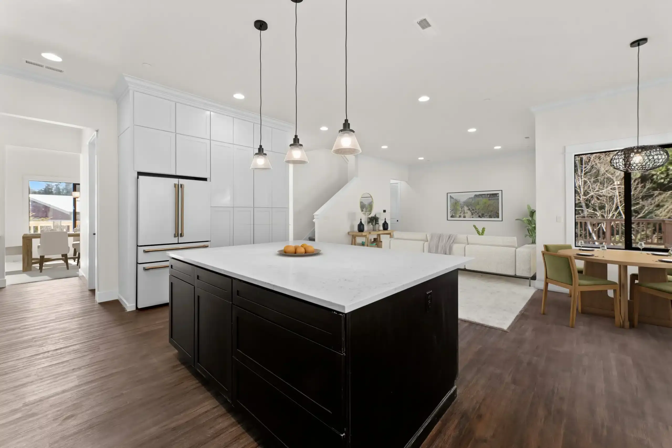 Bright open-plan kitchen and dining area with white cabinets, black island, and wood flooring
