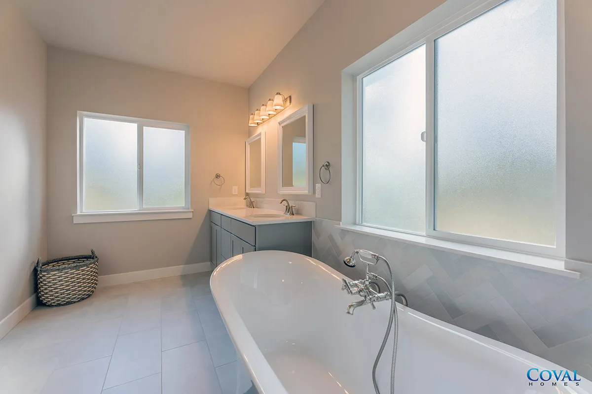 Bright bathroom with a freestanding tub, vanity, and frosted windows creating a clean, airy feel