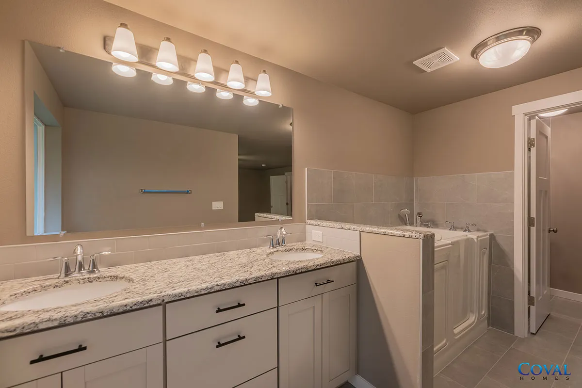 Bright bathroom with double vanity, large mirror, granite countertop, and tiled tub/shower area