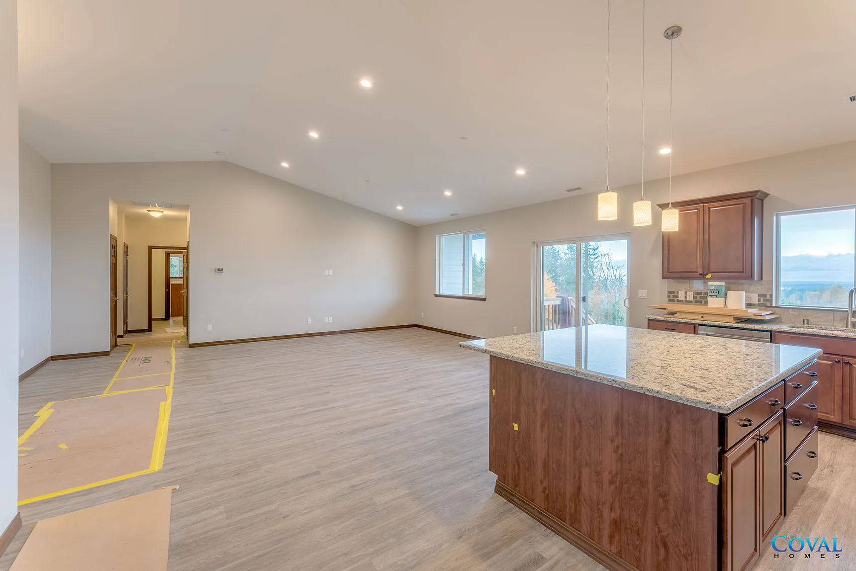 Open-concept kitchen and living room with granite island, carpet, recessed lights, and sliding glass doors