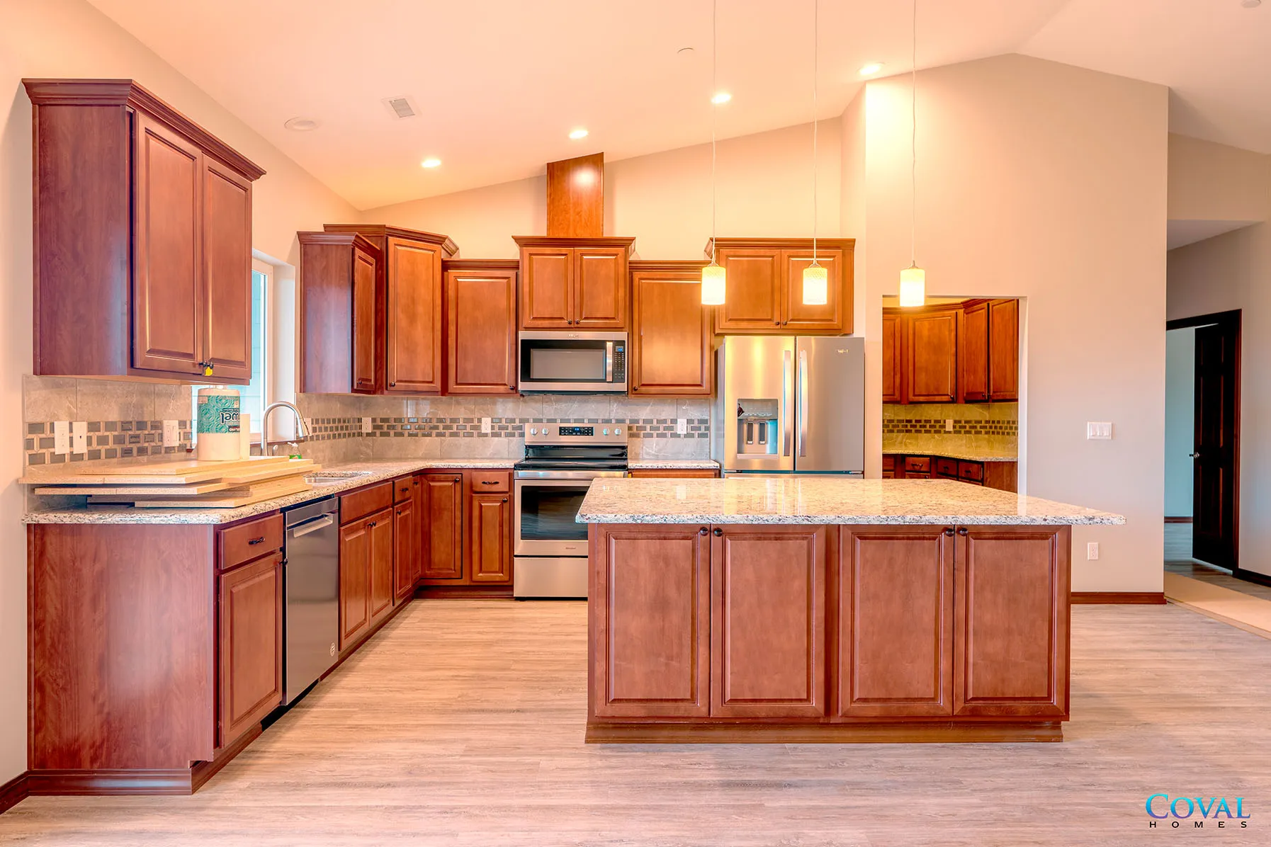 Spacious kitchen with cherry wood cabinets, granite island, stainless appliances, and beige tile floor