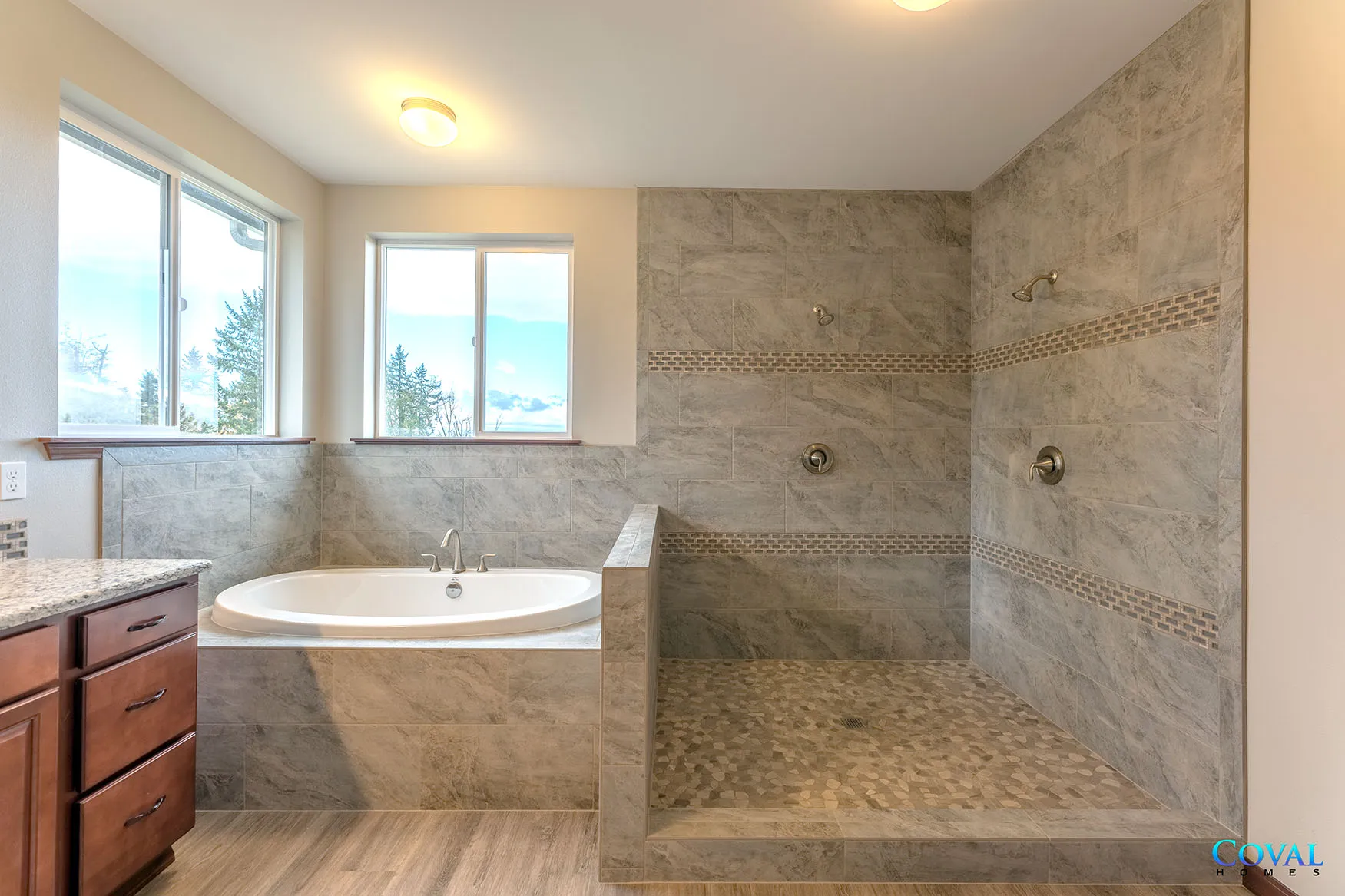 Spacious bathroom with a jetted tub, large walk-in shower, and granite vanity under bright windows.