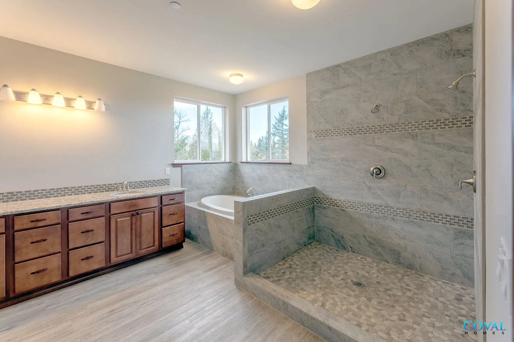 Spacious bathroom with double vanity, large tiled walk-in shower, and a soaking tub by corner windows