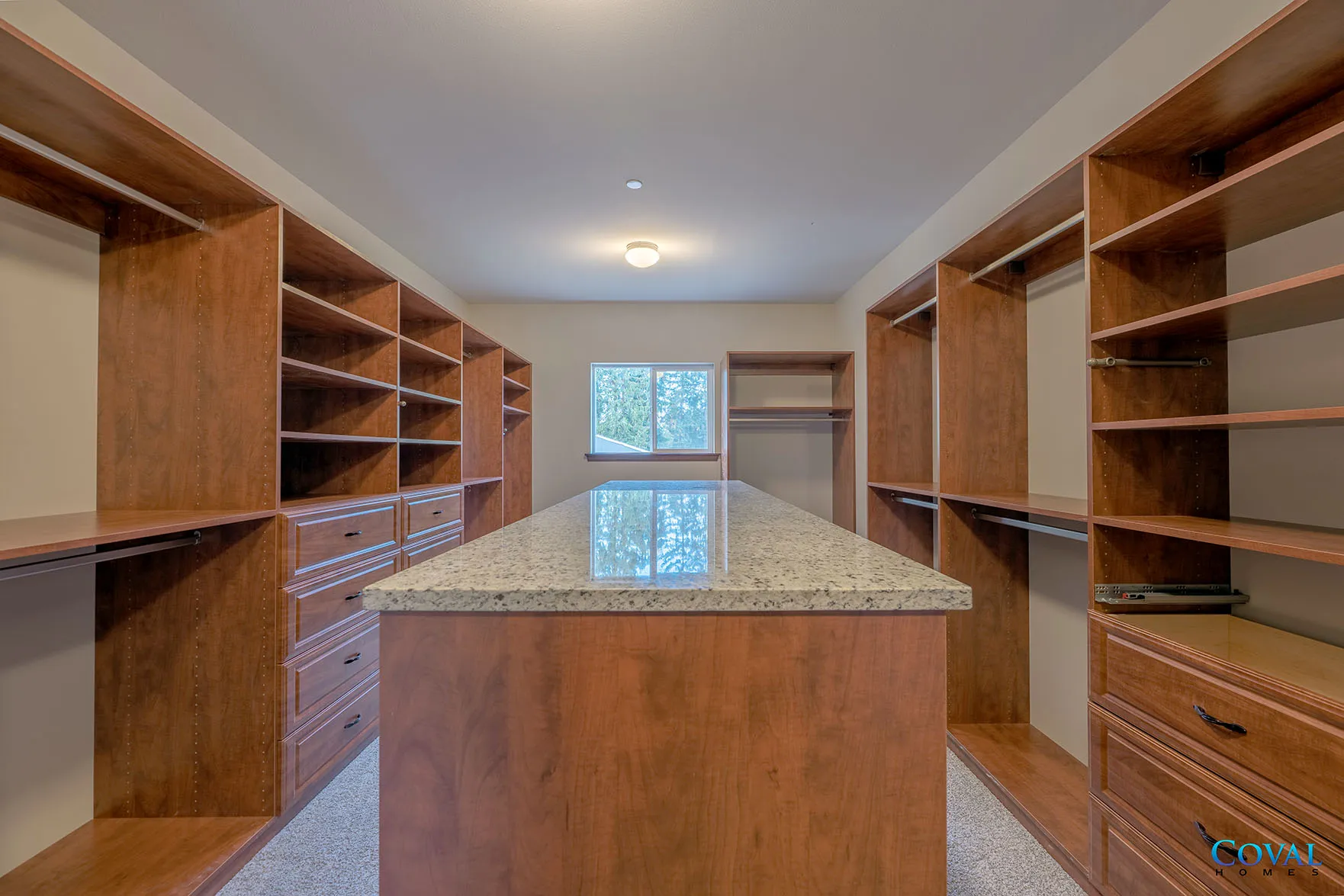 Spacious walk-in closet with wood shelves and a central island under a bright ceiling light.