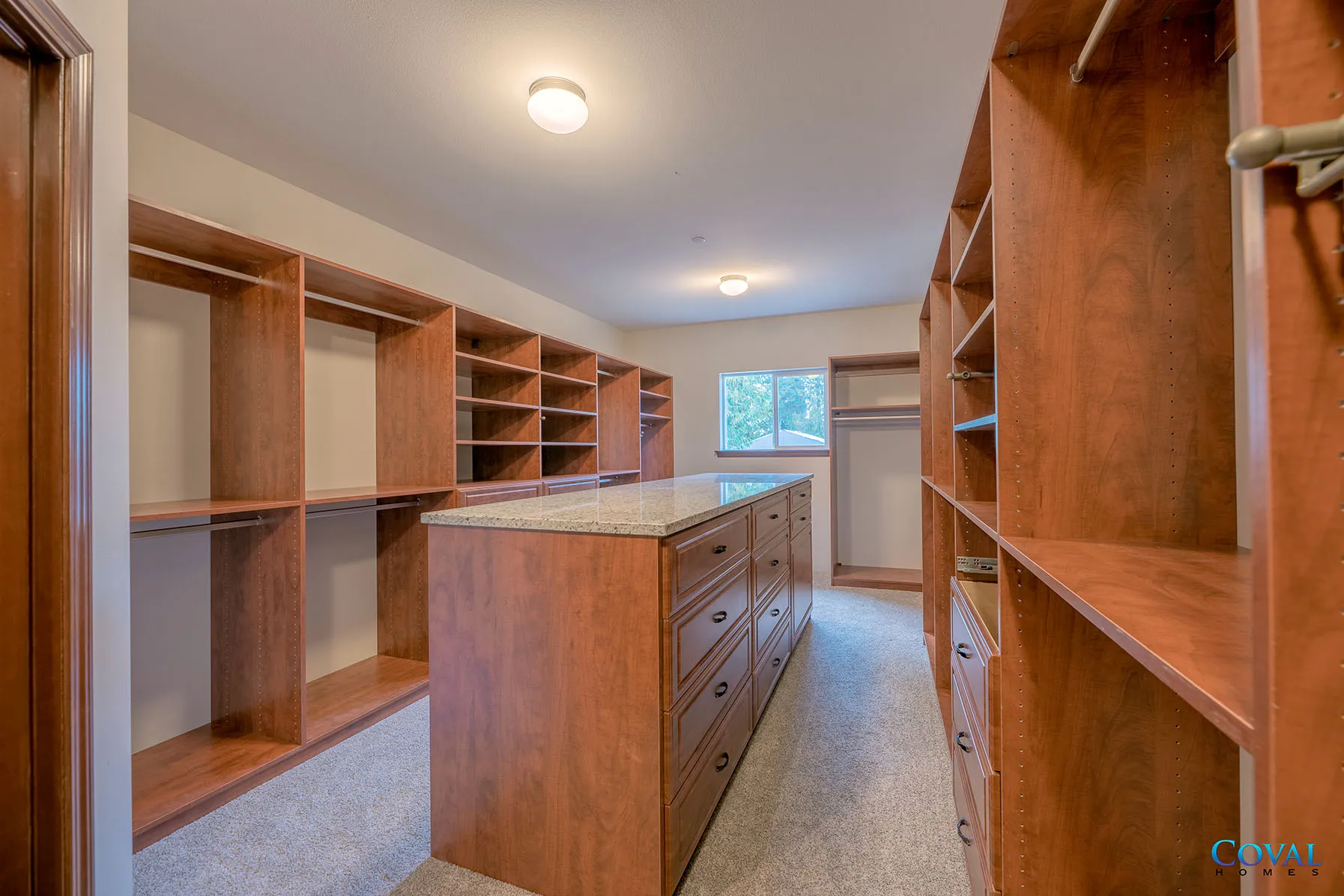 Walk-in closet with wooden shelves, drawers, and a central island under a ceiling light.