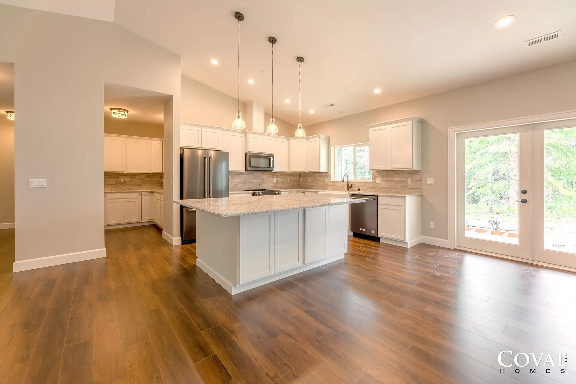 Bright open kitchen and dining area with hardwood floors, island, pendant lights, and large windows.
