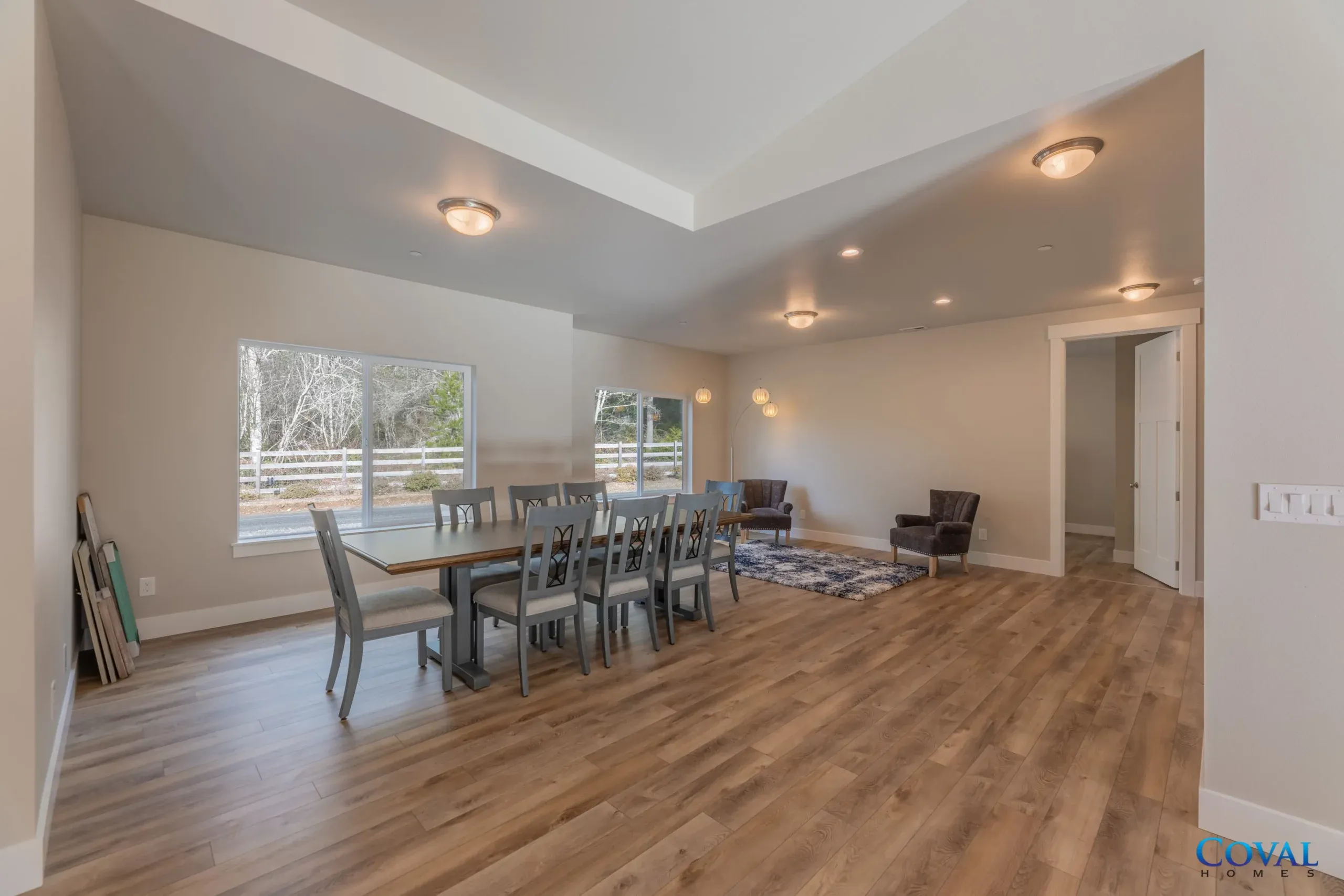Spacious open dining and living room with wood floors, gray table, and recessed lighting