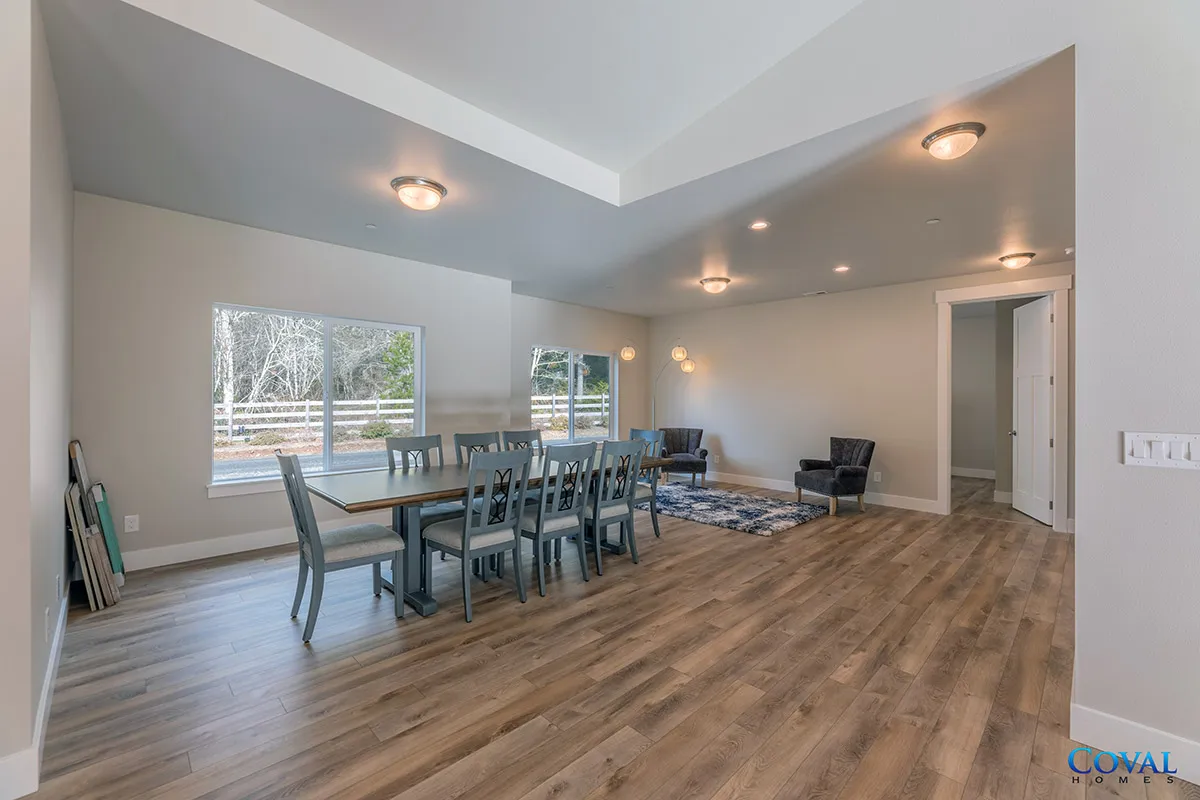 Spacious open dining and living room with wood floors, gray walls, and recessed ceiling lights