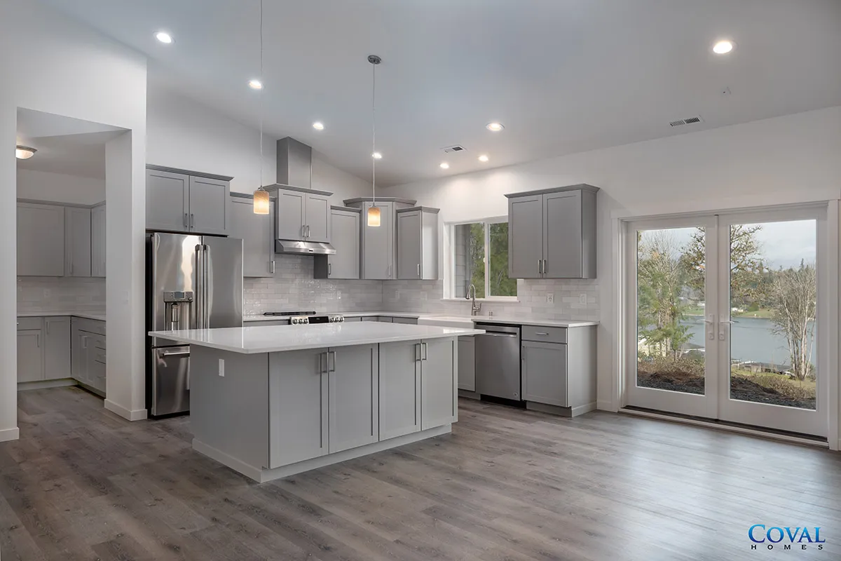 Modern gray kitchen with island, stainless appliances, and large glass doors to the backyard