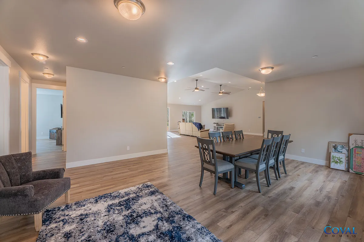 Open-concept living and dining room with wood floors, gray chairs, and a blue rug