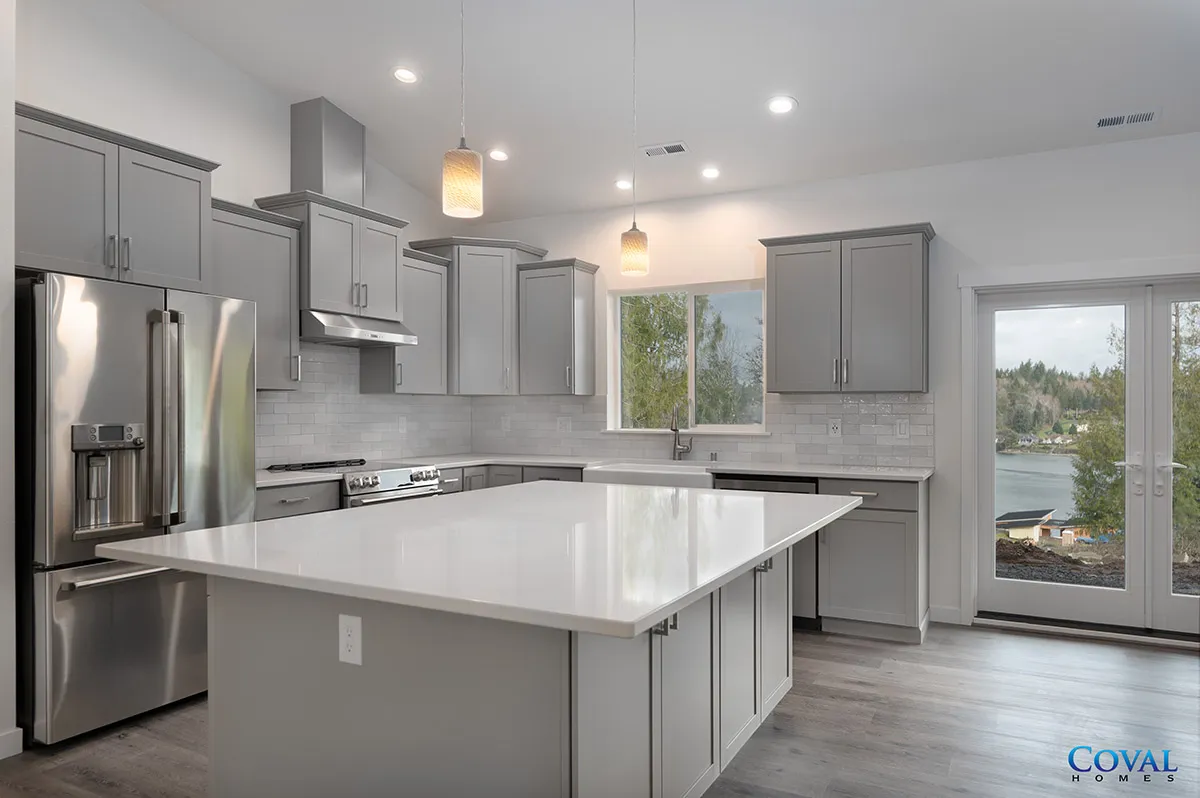 Modern gray kitchen with stainless steel appliances, large white island, and sliding glass doors