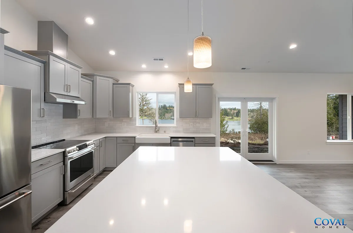 Bright modern kitchen with white island, gray cabinets, stainless appliances, and sliding glass door.