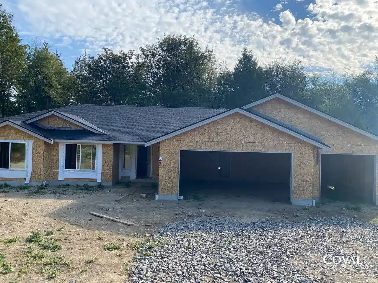 Single-story brick house with dark roof and three-car garage on a gravel driveway