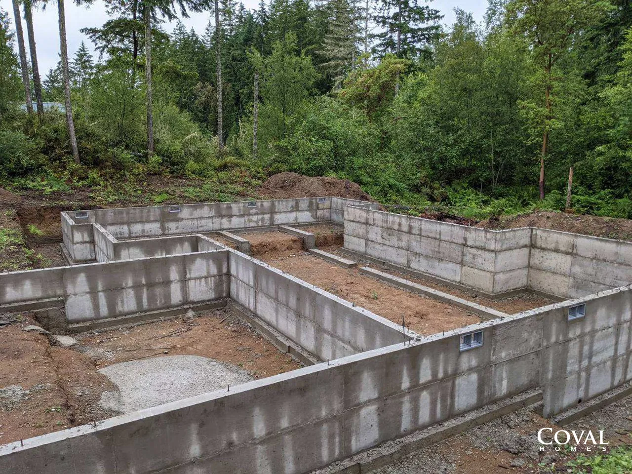 Concrete foundation walls under construction in a wooded area