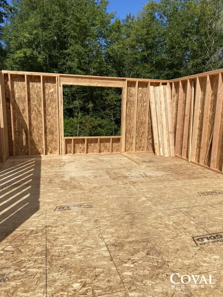 Interior of a framed house under construction with plywood floor and open window and door openings