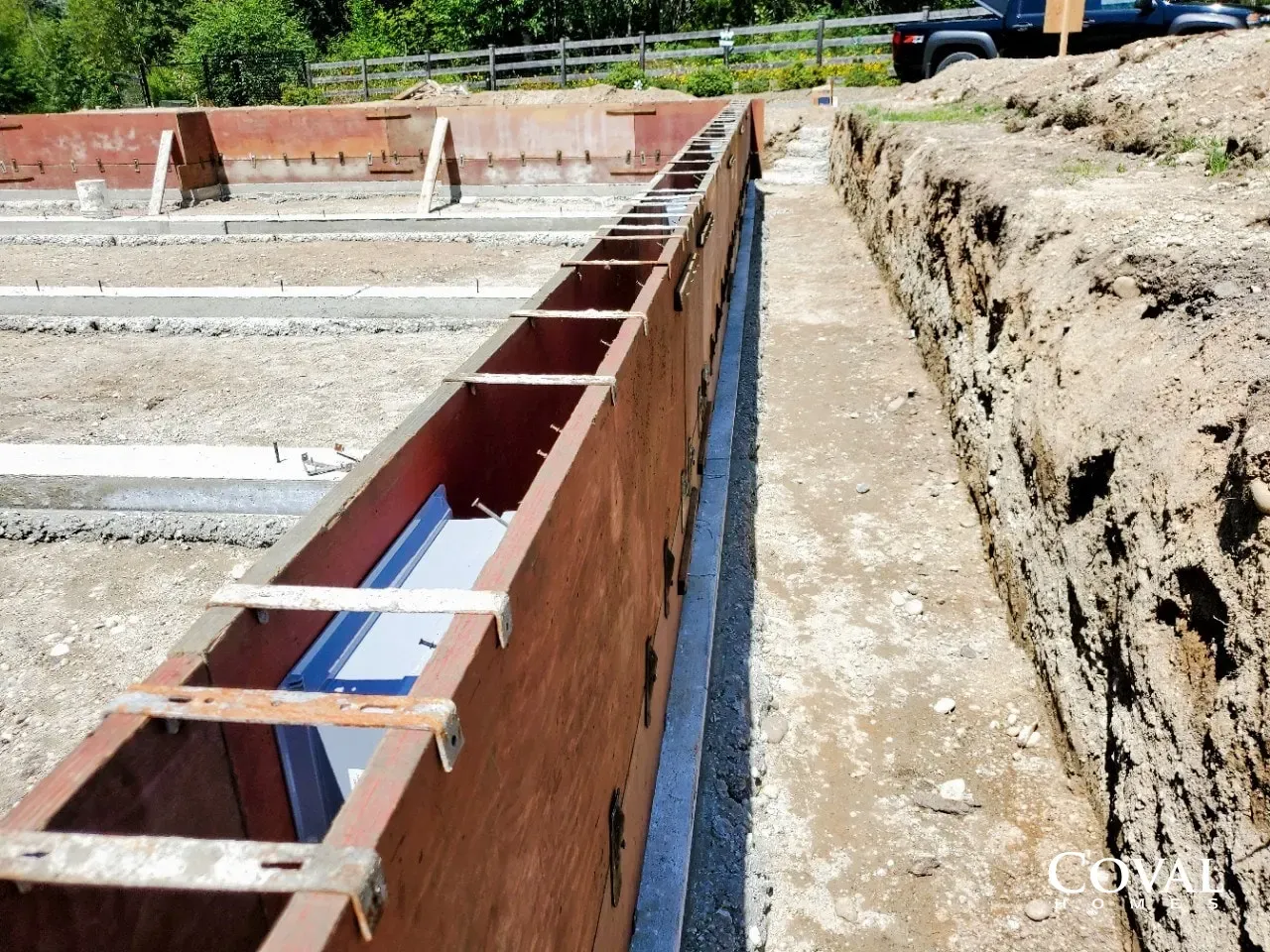Concrete foundation forms beside an excavated trench on a construction site