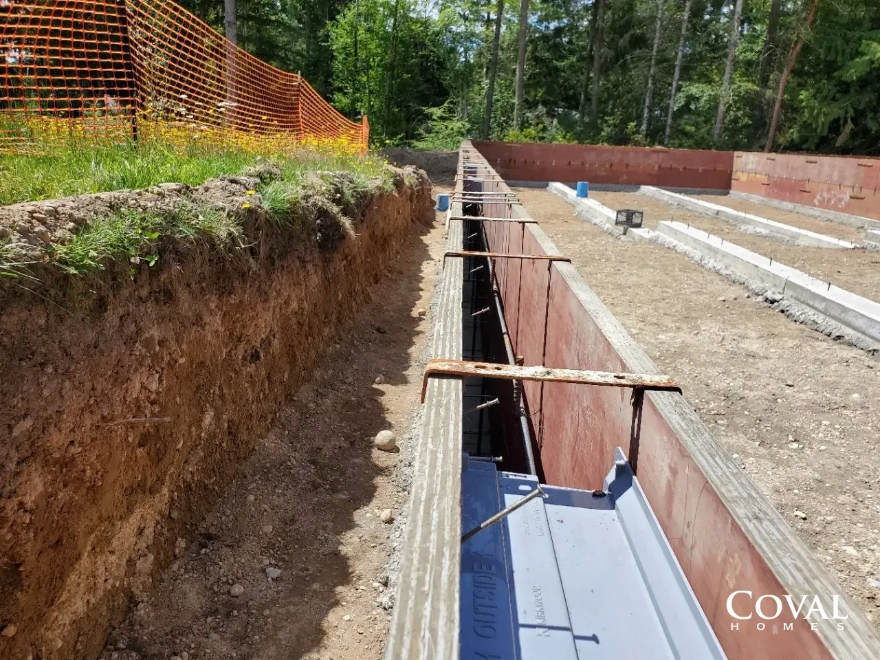 Trench excavation with concrete foundation walls and wooden supports at a construction site