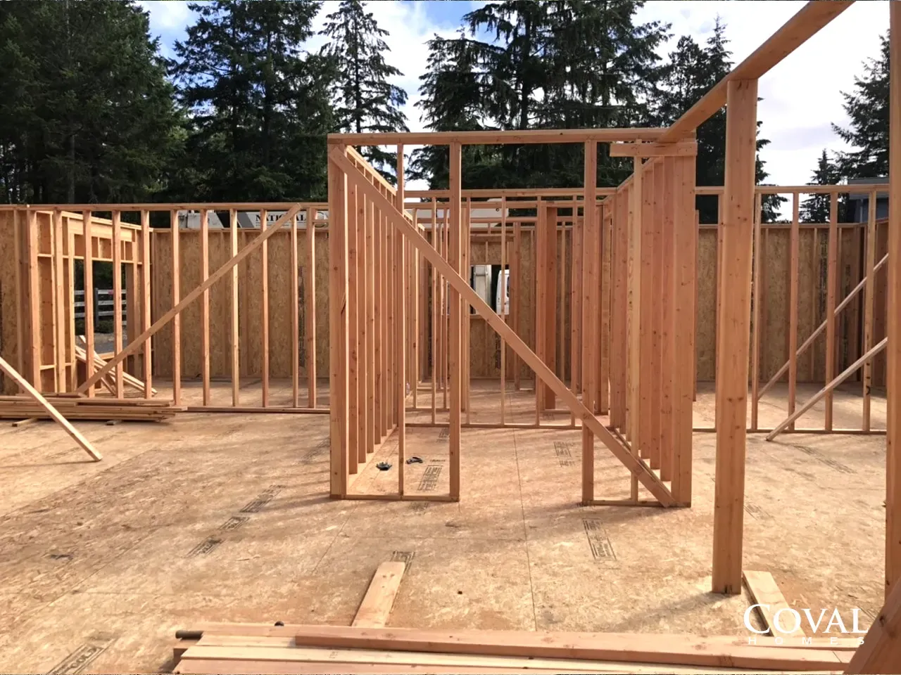 Wooden house framing under construction with exposed studs and open rooms outdoors