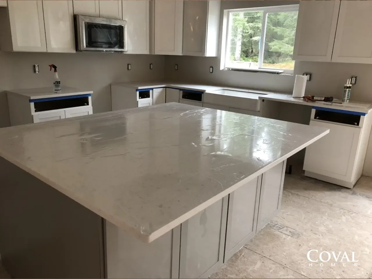 Bright modern kitchen with white cabinets, large island, and stainless steel appliances