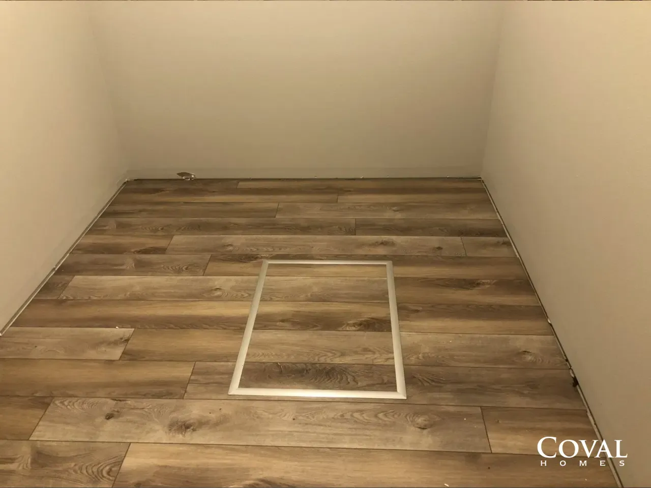 Empty beige room with wood-look floor and a white rectangular floor panel