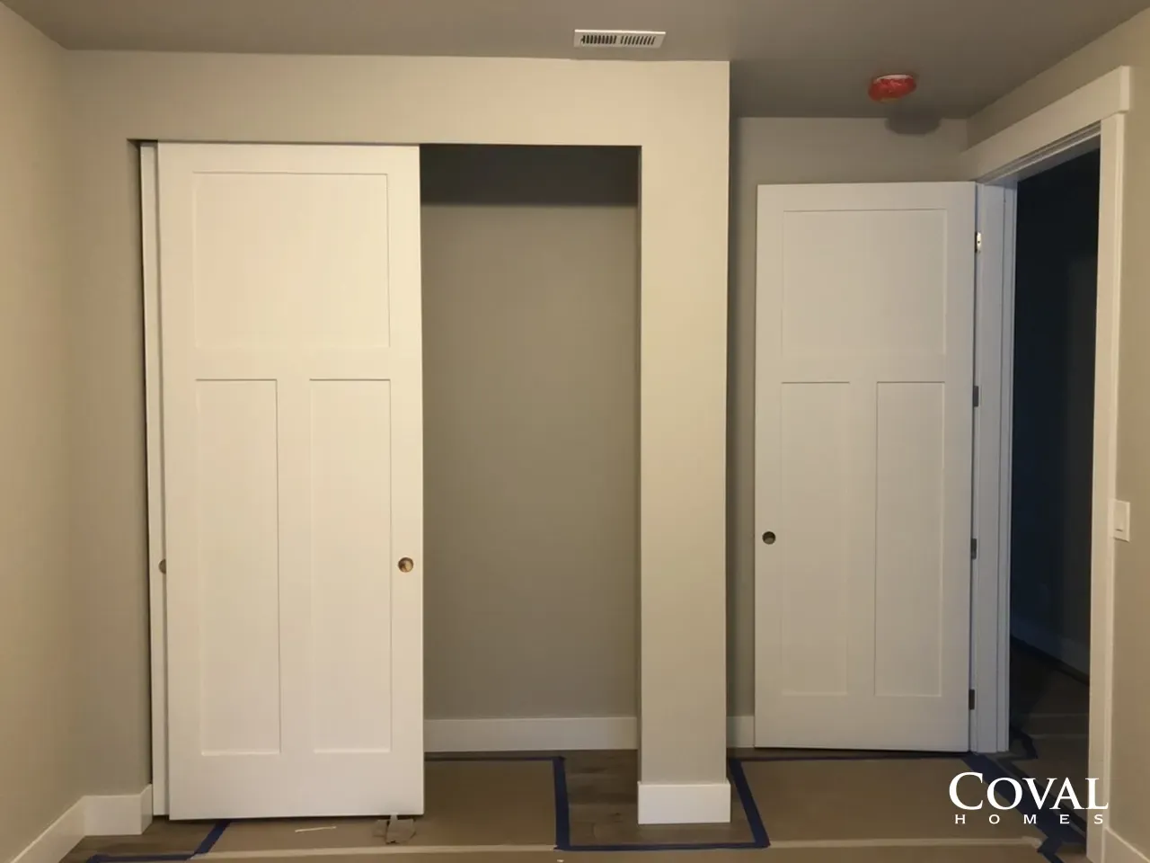 Small room with two white closet doors and a central open closet alcove on beige walls.