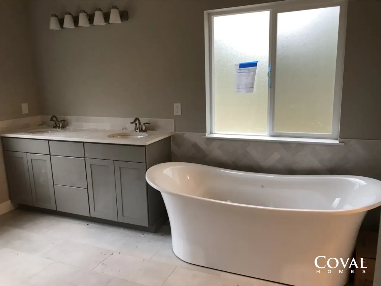 Modern bathroom with double vanity, freestanding tub, and frosted window
