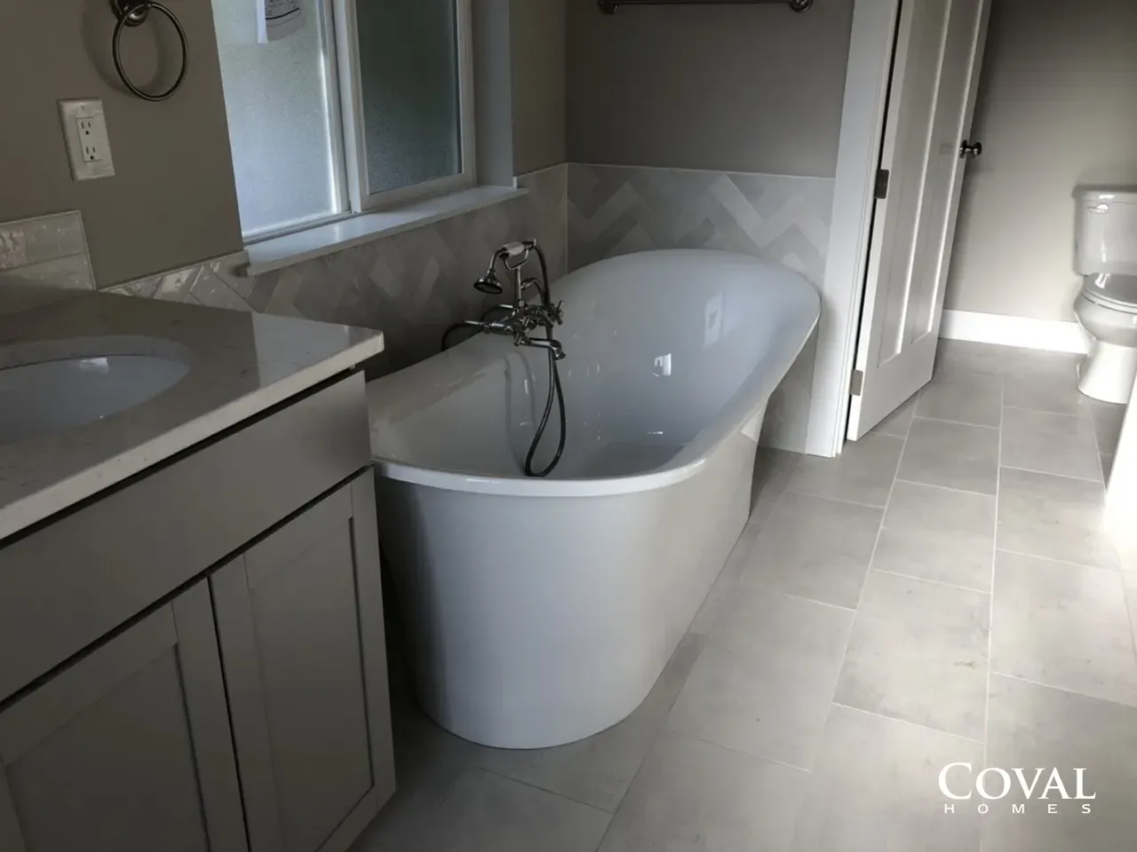 Modern bathroom with a freestanding white tub, vanity sink, and tiled floor