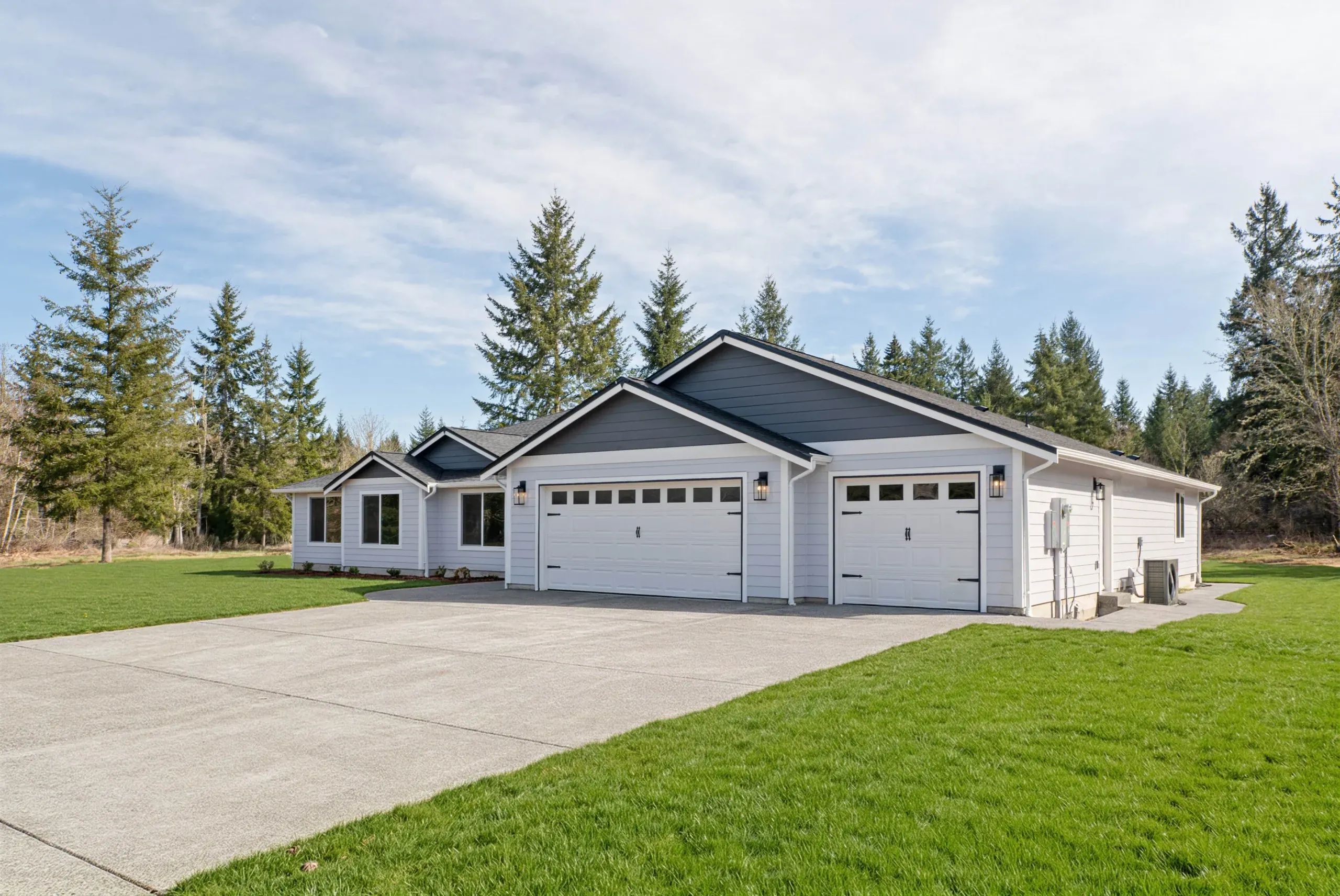 White suburban house with a three-car garage and green lawn under a cloudy sky