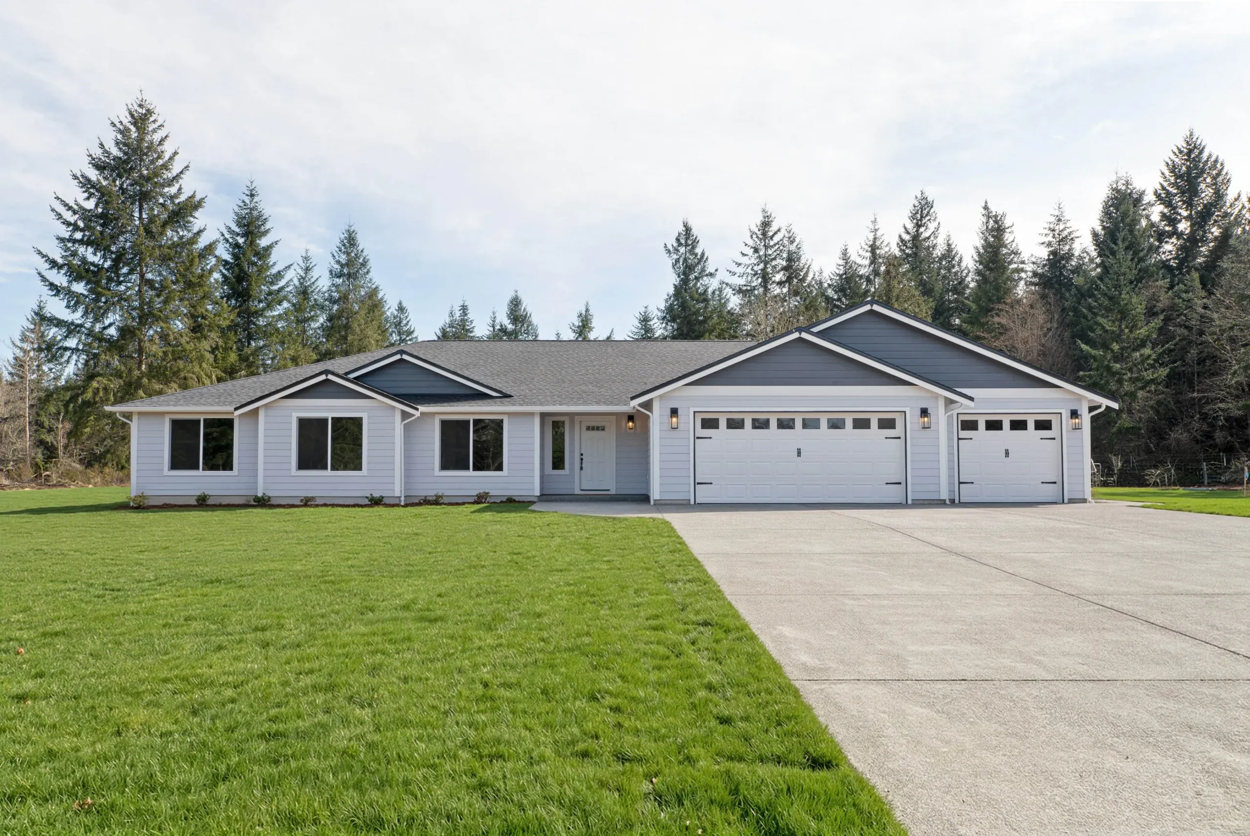 Single-story gray house with a three-car garage and a wide driveway on a grassy lot