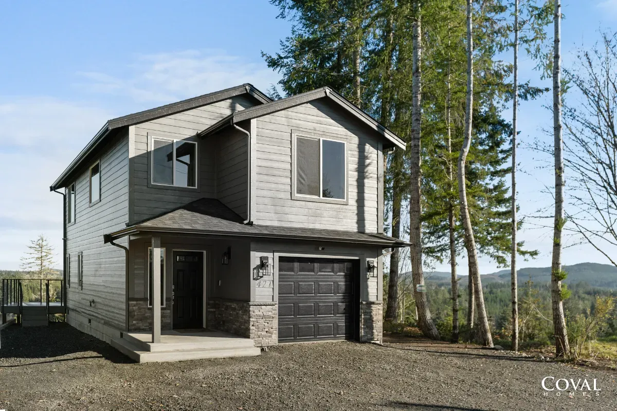 Modern gray two-story house with a garage in a wooded rural setting