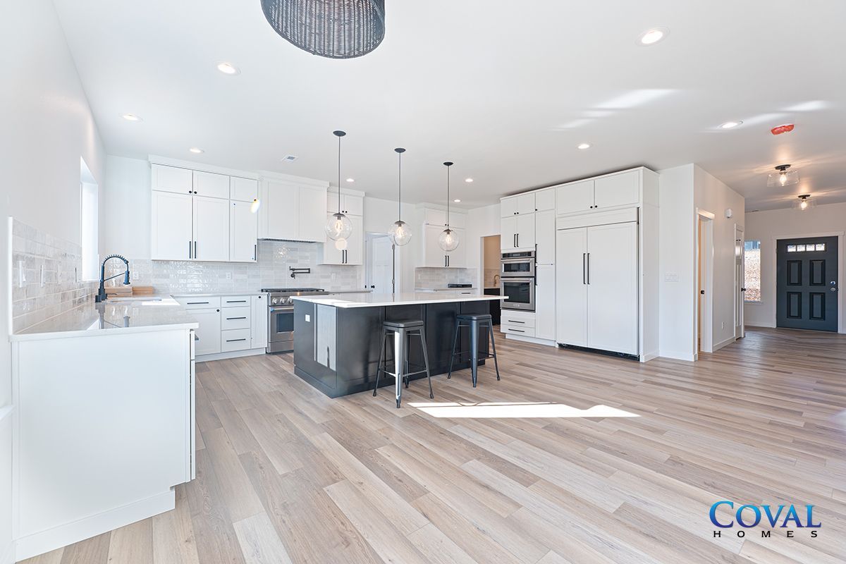 Bright open-plan kitchen with white cabinets, black island, and light wood flooring