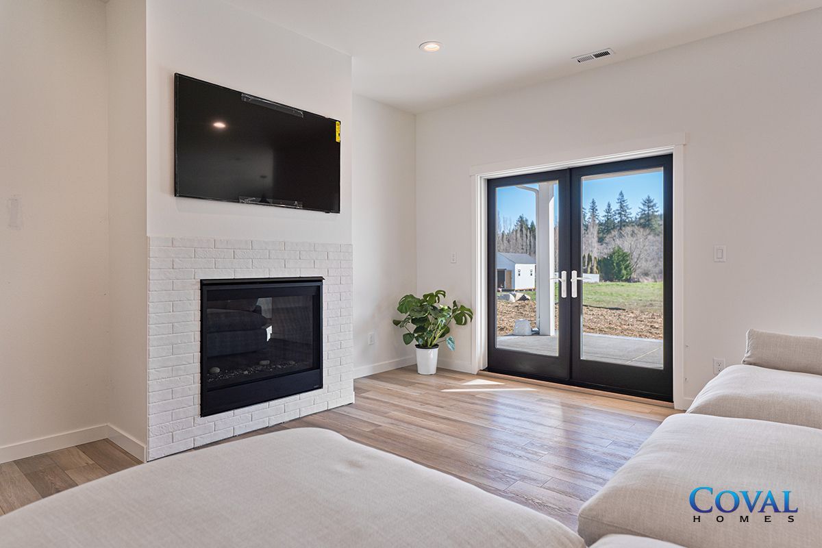 Bright living room with fireplace, wall-mounted TV, and glass doors to a patio.