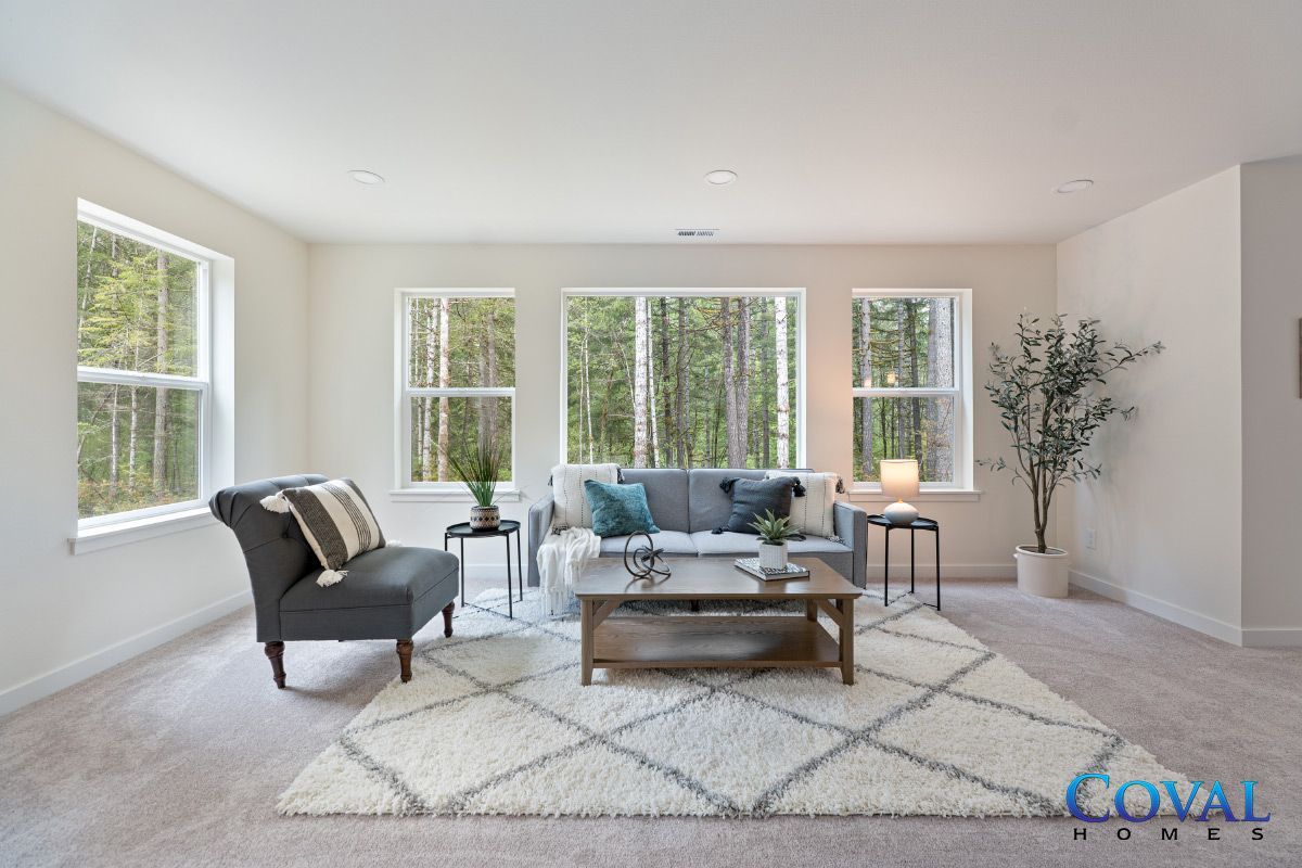 Bright modern living room with gray sofas, coffee table, large windows, and neutral decor