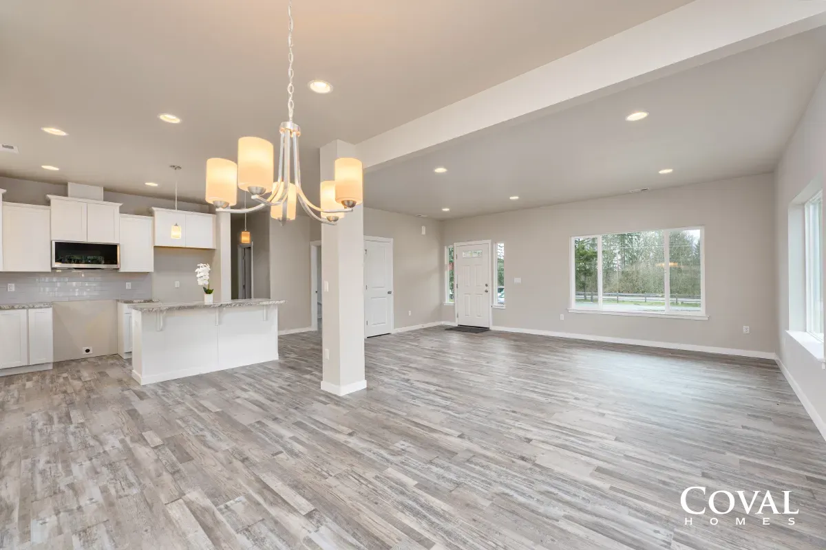 Bright open-concept living room and kitchen with gray floors, white walls, and modern pendant lights